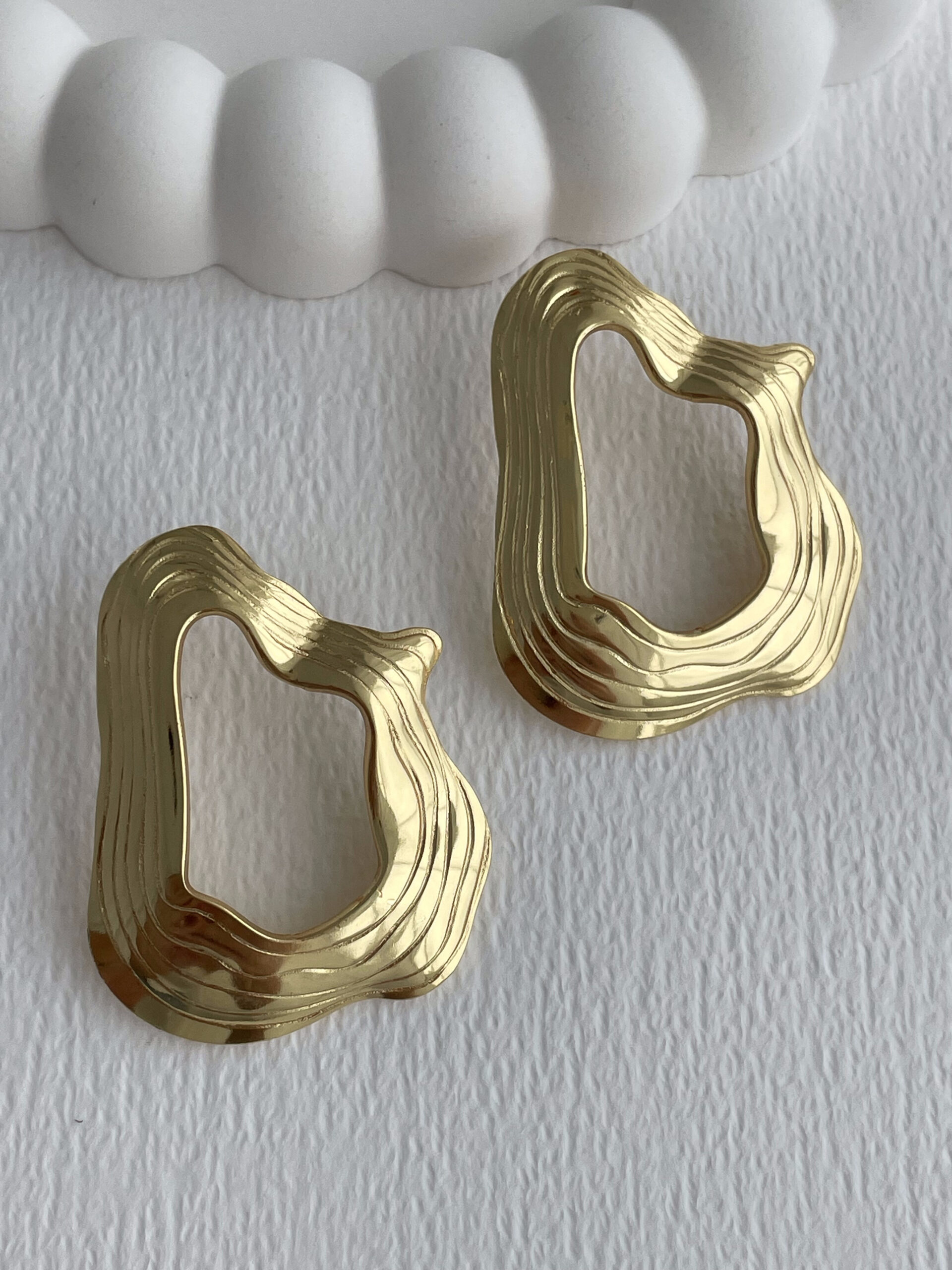 1772112121_0_69a048f9affda.jpg Çelik Desenli Soyut Tasarım Ortası Boş Gold Küpe