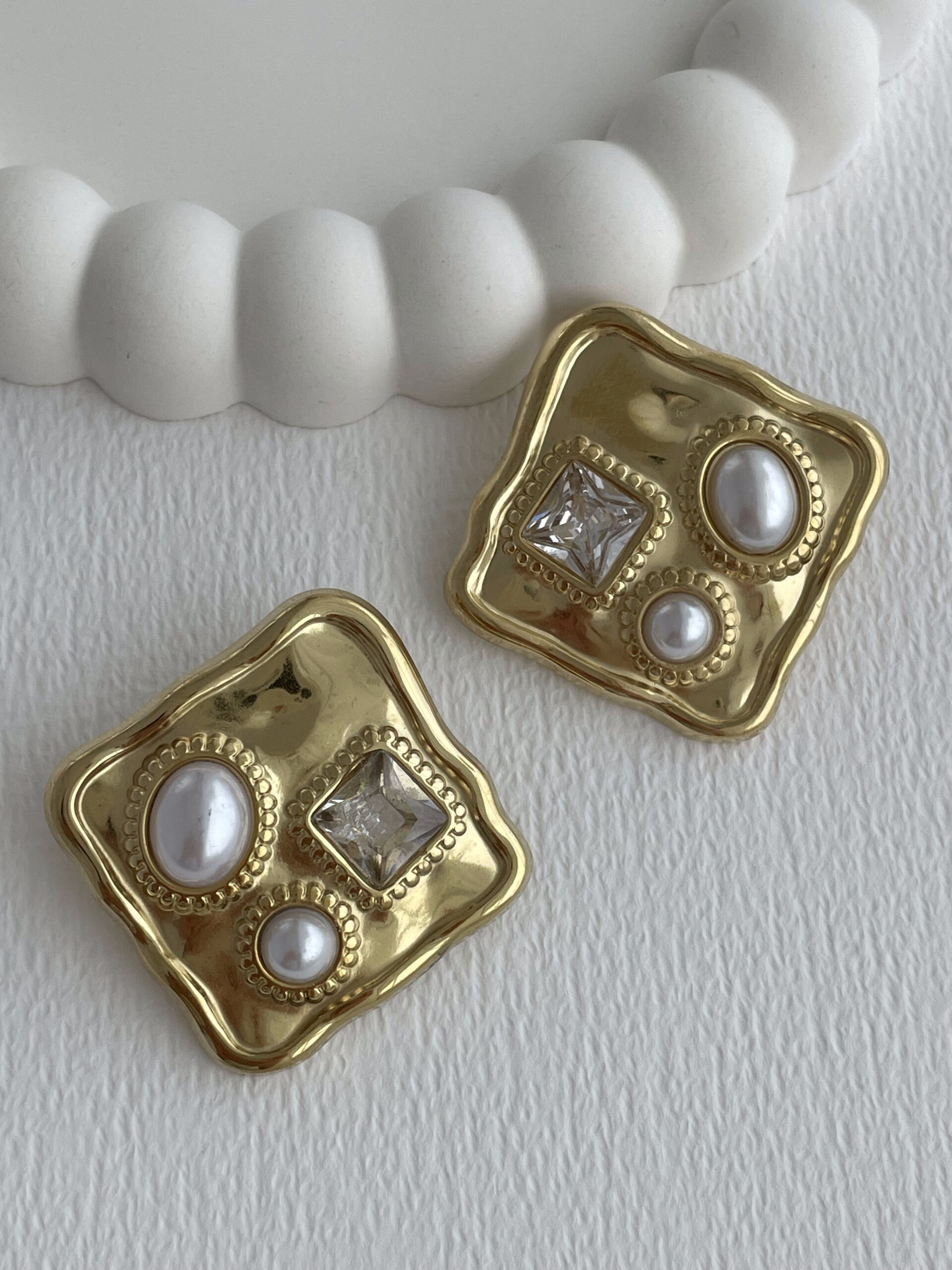 1772115660_0_69a056ccb6b60.jpg Çelik Baget Taşlı İnci Detay Kare Gold Küpe